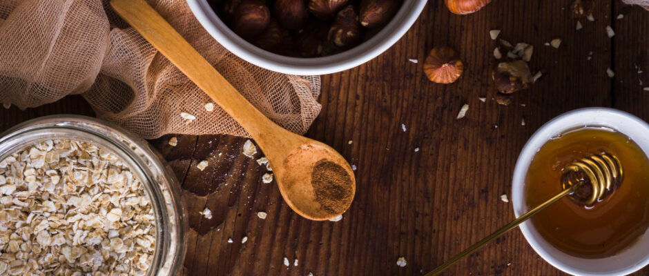 On a wooden table, hazelnuts, oats, and honey are arranged with a spoon, emphasizing premium honey and finest coffee beans.