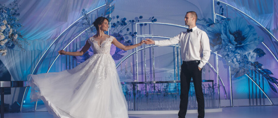 The bride and groom dance joyfully before a blue and white backdrop, highlighting exceptional wedding services and atmosphere.