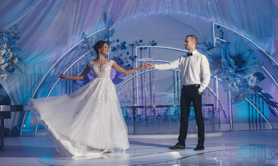 The bride and groom dance joyfully before a blue and white backdrop, highlighting exceptional wedding services and atmosphere.